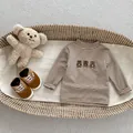 Dettaglio della maglia a righe per neonati con ricamo a orsetto e colletto a lupetto - 73cm / T-shirt a maniche lunghe / Colore avena