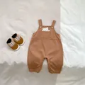 Detail von Baby-Latzhose in Braun mit Bärenmotiv und passenden weichen Lauflernschuhen - Braun / 66cm