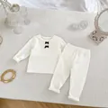 Detalle del conjunto de ropa de casa para bebé en color crema con textura de canalé - Blanco / 66cm