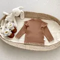 Nahaufnahme brauner Strickpullover mit Rüschen, Rippstruktur und Größenetikett - Größe 73 / Braun Unterteil
