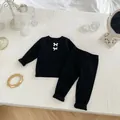 Detalle de conjunto acanalado para bebé con lazos blancos sobre tela suave negra - Negro / 66cm