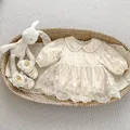 Flat lay of baby lace romper, matching shoes, and plush rabbit in a woven basket - 66cm / Apricot