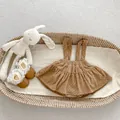 Flat lay of brown polka dot corduroy baby pinafore dress in a woven basket display - 66 / Brown Polka Dot