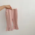 Detail view of pink flared leggings with ribbed texture, side slit, and bow with gold bell - 66 / Pink