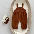 Detail von Baby-Cord-Strampler mit Knöpfen und passenden Schleifenschuhen im Weidenkorb - 66cm / Karamellfarbene Cord-Latzhose