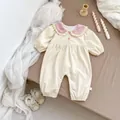 Detail of corduroy baby romper featuring ruffles and snap buttons on a warm background - 66 / Apricot