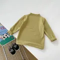 Détail d'un t-shirt enfant vert moutarde à manches longues avec col roulé et revers - 66CM / Vert