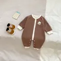 Detail van babyrompertje met berenborduursel en drukknoopsluiting op zachte stof - 66CM