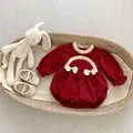 Detail of red baby romper with ruffled collar and matching soft-sole shoes on woven basket - 66cm / Red