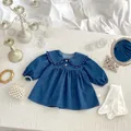 Detail of dark blue denim baby dress featuring ruffle collar and wooden button accents - Size 80 / Dresses