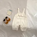 Detalle de peto vaquero beige para bebé con bolsillo en el pecho y broches metálicos - Albaricoque / 73cm