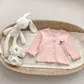 Detail van roze geribbelde baby-top met strikborduurwerk en label maat 66 op zachte stof - 66cm / Roze Top