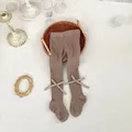Detail of baby footed tights featuring rib-knit texture and ankle ribbon bow decoration - Grey-brown