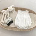 Detail of tweed baby romper with bow neckline and lace shoes in a woven cradle - White Bodysuit / 66cm