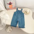Détail d'une salopette en jean pour bébé avec ourlet à volants et boutons-pression - 73 / Salopette en Jean Bleu à Volants