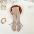 Detail of baby girl knitted tights in khaki featuring a side silk bow and ribbed texture - Camel Beige