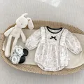 Detail of floral baby bodysuit with lace shoes and bunny toy in a woven basket - Long Sleeve / 80cm
