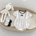Close-up of floral baby romper with delicate lace bow and matching black soft shoes - T-Shirts / 66cm