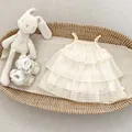 Detaillierte Makroaufnahme eines cremefarbenen Stufenkleides mit Bogenstickerei für Babys - Aprikose / 73cm