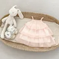 Detailaufnahme von hellrosa gestuftem Babykleid mit gestickten Schleifen in einem Korb - Rosa / 73cm