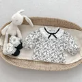 Close-up of floral baby top with lace collar and ribbon bow in a woven basket - 66cm / Floral Long Sleeve Shirt