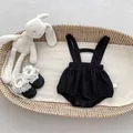 Close-up of black waffle texture baby romper with snap buttons in a woven basket - 66cm / Black Strap Romper