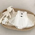 Detail of white infant sleeveless mesh romper dress with black bows in a wicker basket - White / 66cm