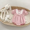 Detail of pink baby romper featuring white lace collar with bows and size 66 label - 66 / Pink