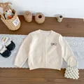 Gebreid beige babyvest met ruitpatroon en geborduurde strik op houten achtergrond - Ruitpatroon Gebreid Vest / Abrikoos / 73cm