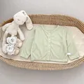 Detail van lichtgroen babyvest op rieten mand met een zachte pluchen konijn - Groen / 73cm