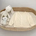 Detailopname van lichtgeel gebreid vest met verticale ribbeltextuur en witte knopen - Abrikoos / 73cm