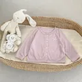 Detail van lichtroze baby zonnebrandvest met knopen en strikje in babywieg - 73cm / Paars