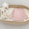 Detailed close-up of pink textured baby bodysuit with white size tag in a woven basket - 66 / Pink
