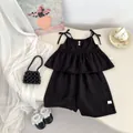 Detail of girls' black linen set featuring ruffle strap top with bow and matching shorts - 73 / Black