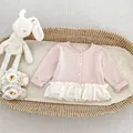 Detail van roze gebreid vest voor babymeisjes met kantrand en maattabel 73 in een mand - 73cm / Roze