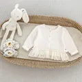 Detail van wit gebreid babyvestje met kanten rand en geweven wafelstructuur textuur - 73cm / Abrikoos