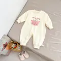 Detailweergave van beige babyromper met konijnenprint en drukknoppen op een zacht bed - Maat 66 / Beige Abrikoos