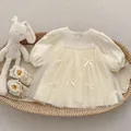 Flat lay of cream long-sleeve mesh dress with bow detail and lace baby shoes - 73cm / Dresses / Cream