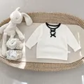 Detail van babymeisjes katoenen shirt met zwarte strikjes en kanten babyschoentjes - 73cm / Wit