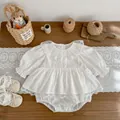 Flat lay of baby lace long sleeve romper set with matching soft shoes on wooden desk - White / 66cm