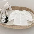 Primer plano de camisa blanca para niña con cuello de encaje y puños con volantes - 73cm / Camisas