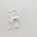 Detail of baby leggings with pink heart knee patches on soft white knit fabric - 66 / White