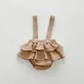 Detail of waffle fabric baby romper showing ruffled hem and adjustable strap buttons - 66cm / Jumpsuits / Brown