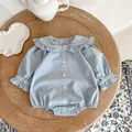 Close-up of light blue baby romper featuring ruffled doll collar and wooden table setting - 100cm / Blue