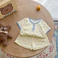 Detail of floral baby cotton set with plaid piping and buttons on wooden table - Blue Plaid Floral