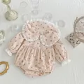 Detailed view of floral baby bodysuit with lace collar and snap button closure - Apricot / 80