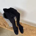Close-up of black ribbed knit leggings showing soft cotton texture on a rustic wooden bench - Bottoms / Black / M (2-4 Years)