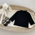 Infant girl ribbed black long sleeve tee with ruffle trim in a cozy woven basket - 66 / Black