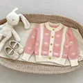 Pink and cream knitted baby cardigan featuring subtle bow patterns and wooden buttons - Size 66 / Pink Cardigan