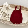 Donkerrode gebreide babyromper met kabelpatroon en houten knopen in geweven wieg - 66cm / Kersenrood Strampler